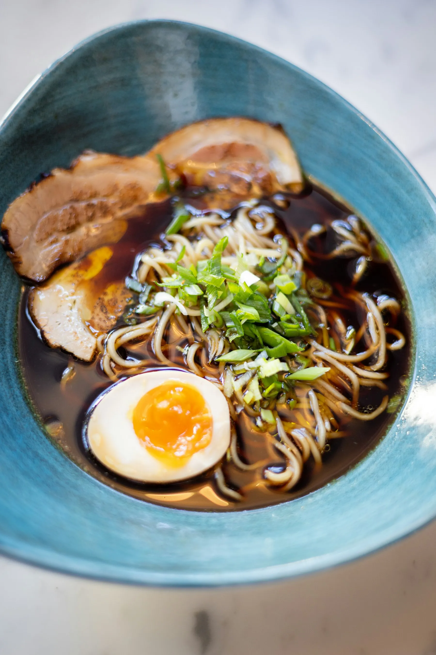 Ramen mit Schweinebauch und Ei in einer türkisen Schale